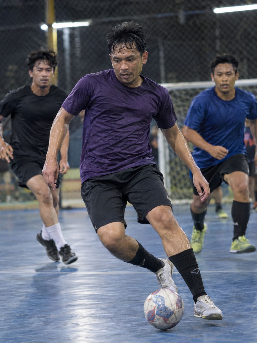 Pria bermain futsal di lapangan indoor